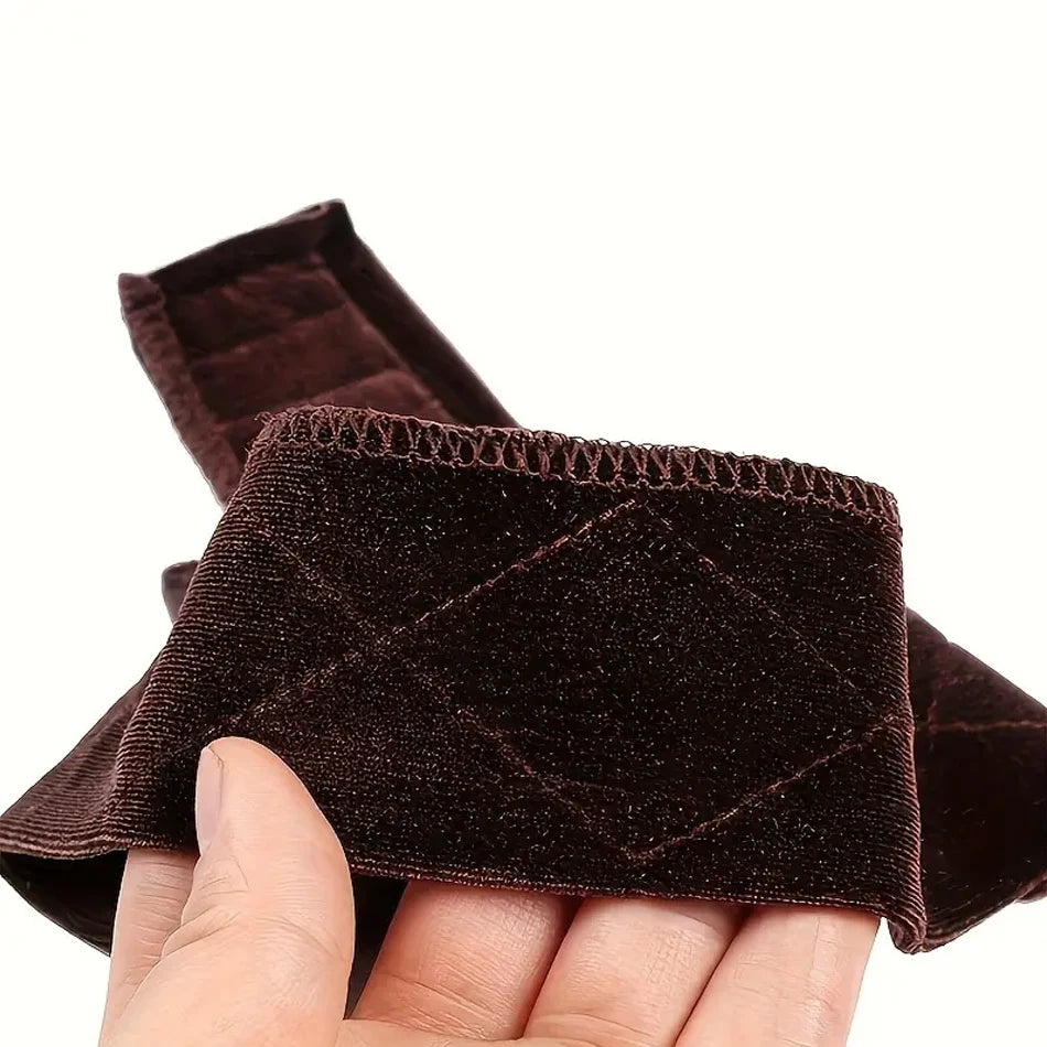 A hand is holding a dark brown, velvet wig grip headband.