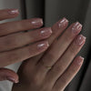 Close-up of a hand displaying elegant nude pink striped press-on nails with an almond shape