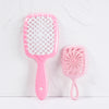 A pink detangling hair comb with a wide, perforated teeth design is shown against a white background.