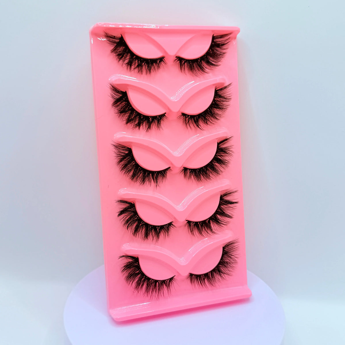 Plateau en plastique rose contenant cinq paires de faux cils dramatiques.