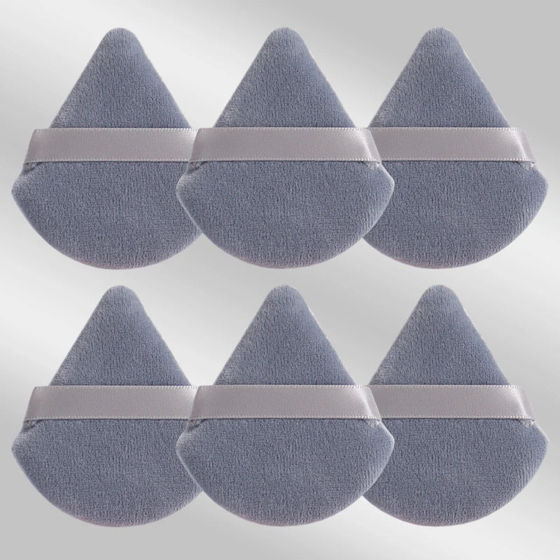 Un ensemble de six éponges de maquillage triangulaires en tissu gris doux avec des bandes rose pâle.