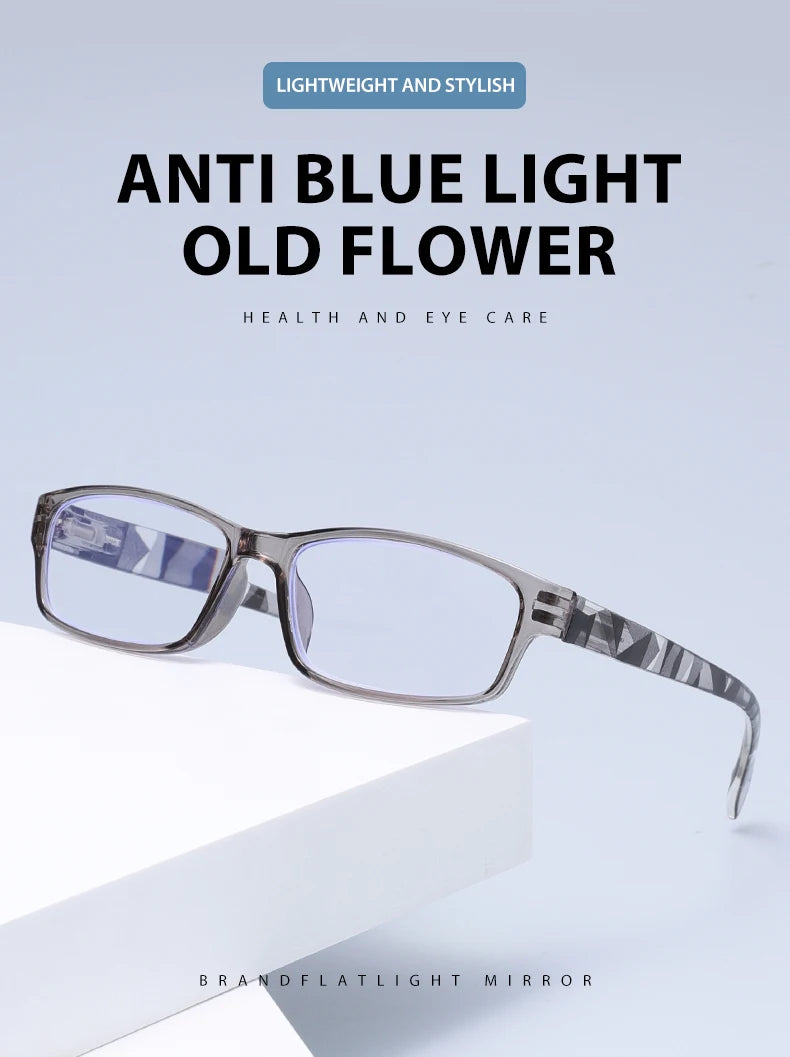 Un par de elegantes gafas de lectura antirluz azul con montura gris y lentes transparentes sobre una superficie blanca.
