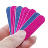 A hand holds a set of double-sided mini nail files in various shades of blue and pink.