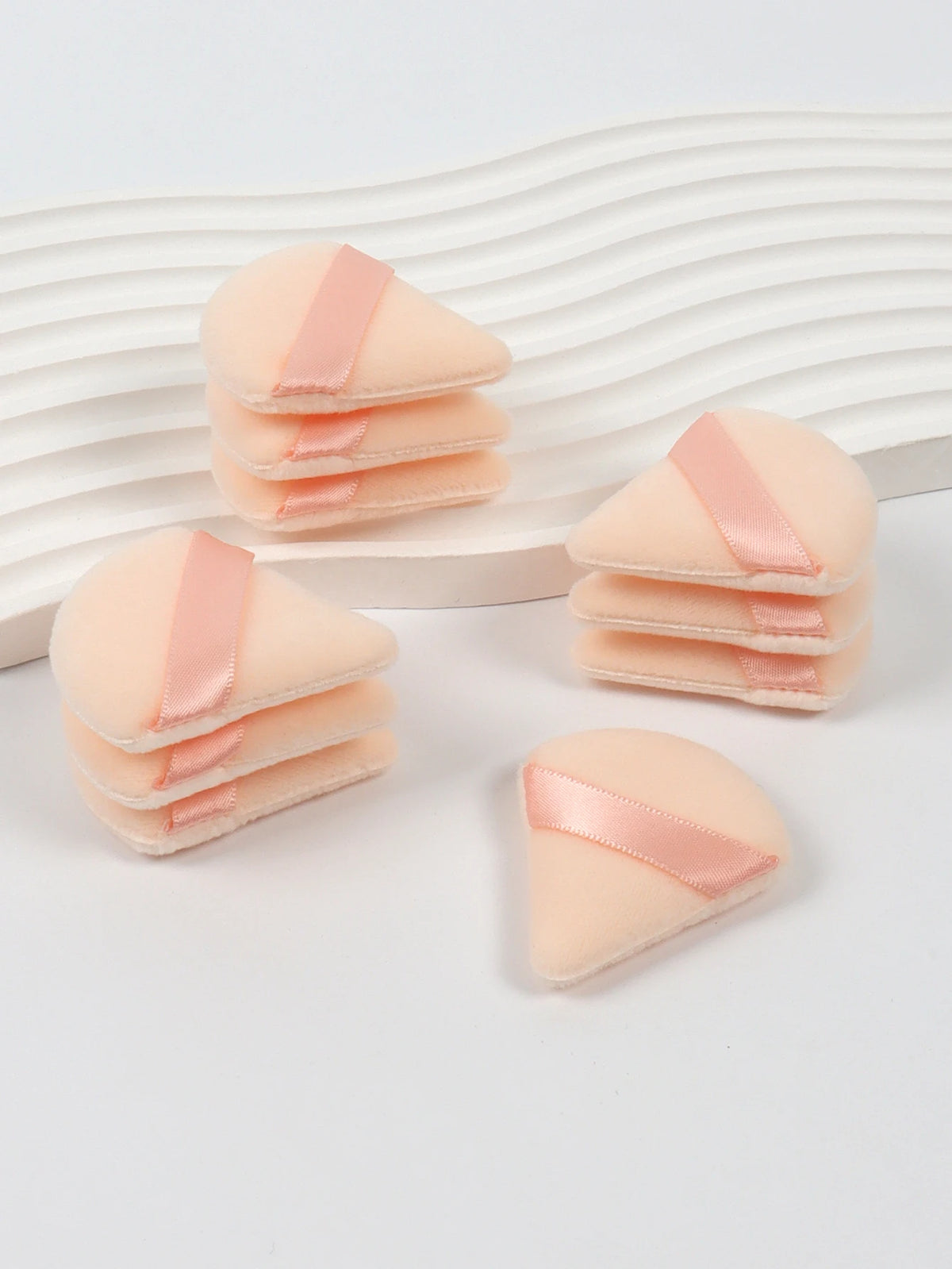 Un ensemble de puffs triangulaires roses avec des rubans de satin sur un fond blanc.