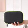 A hand holds a black hard-shell travel case with a lime green trim for electric shavers.