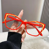 A hand holds a pair of bright orange and yellow cat eye reading glasses against a light background.