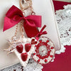 A set of hand holding makeup mirrors with pink and gold accents and a red satin bow on a white background.