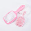 A pink detangling hair comb with a silicone handle is shown next to a white stone.