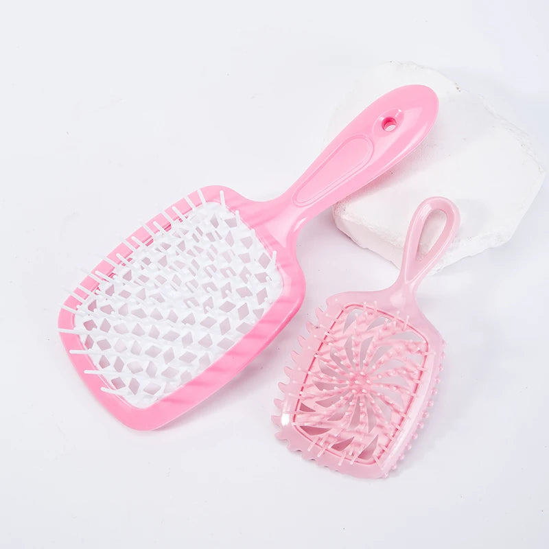 A pink detangling hair comb with a silicone handle is shown next to a white stone.