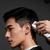 A man is using a professional electric hair clipper on his side profile to groom his haircut.