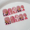 Un set de uñas postizas de perla rosa nude con base rosa, estampado de leopardo negro y acentos dorados.