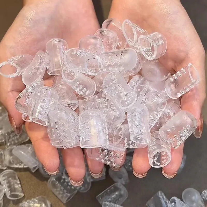 A hand holds a pile of clear silicone toe covers for foot protection.