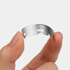 A hand holds a single professional stainless steel razor blade against a white background.