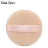 A round, light peach colored makeup puff with a pink ribbon attached.