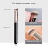 A long, black concealer brush with soft bristles and a diagonal curved surface for precise application.
