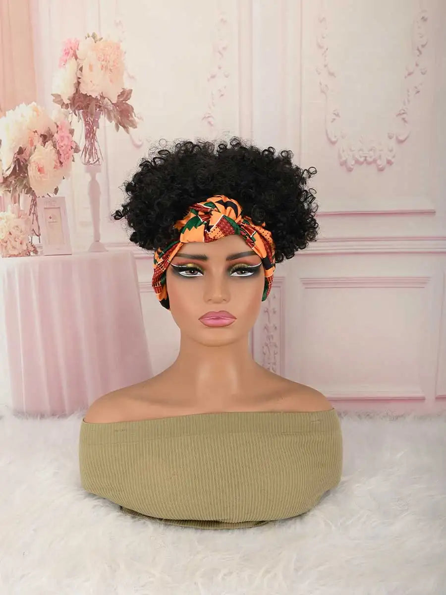 A mannequin head wearing an orange patterned afro puff turban wig with a green top and light pink background.