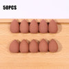 Fifty pink makeup sponge puffs arranged in a row on a wooden surface.