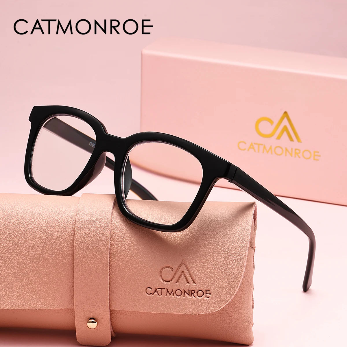 A pair of black square reading glasses resting on a pink leather case with a CatMonroe logo.