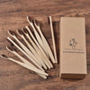 Une boîte contenant un pack de 10 brosses à dents en bambou naturel, présentée sur une surface en bois.