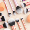 Una colección de 12 brochas de maquillaje profesionales en varios tonos de rosa y plata sobre un fondo claro.