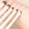 A set of five white makeup brushes with natural colored tips are shown on a person's arm.