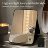 A high-end light luxury minimalist foldable makeup mirror resting on a dark surface next to a glass and a candle.