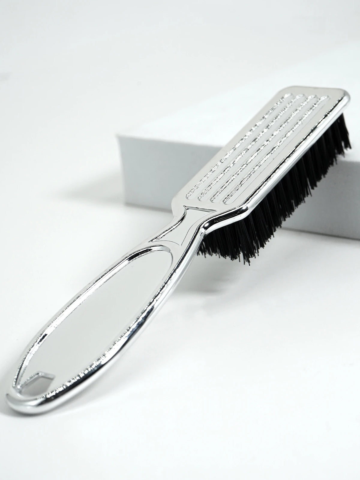 A silver professional duster brush with black bristles is shown on a white background.