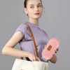 A woman holds a pink heated abdominal massage belt in her hand, against a gray background.
