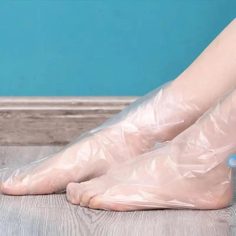 Chaussettes hydratantes pour les pieds jetables disposées sur une surface en bois avec un fond bleu.