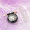 A black nail glitter powder set with a holographic chrome finish and wooden applicator, displayed on purple glitter fabric.