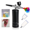 A portable airbrush set with a black body and silver nozzle, featuring multiple paint colors and disposable cartridges.