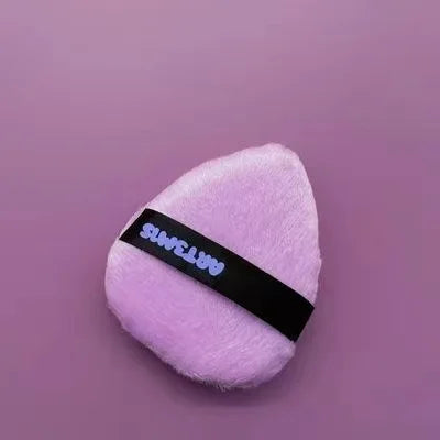 Poudrette cosmétique rose à flockage avec une bande noire sur fond violet.