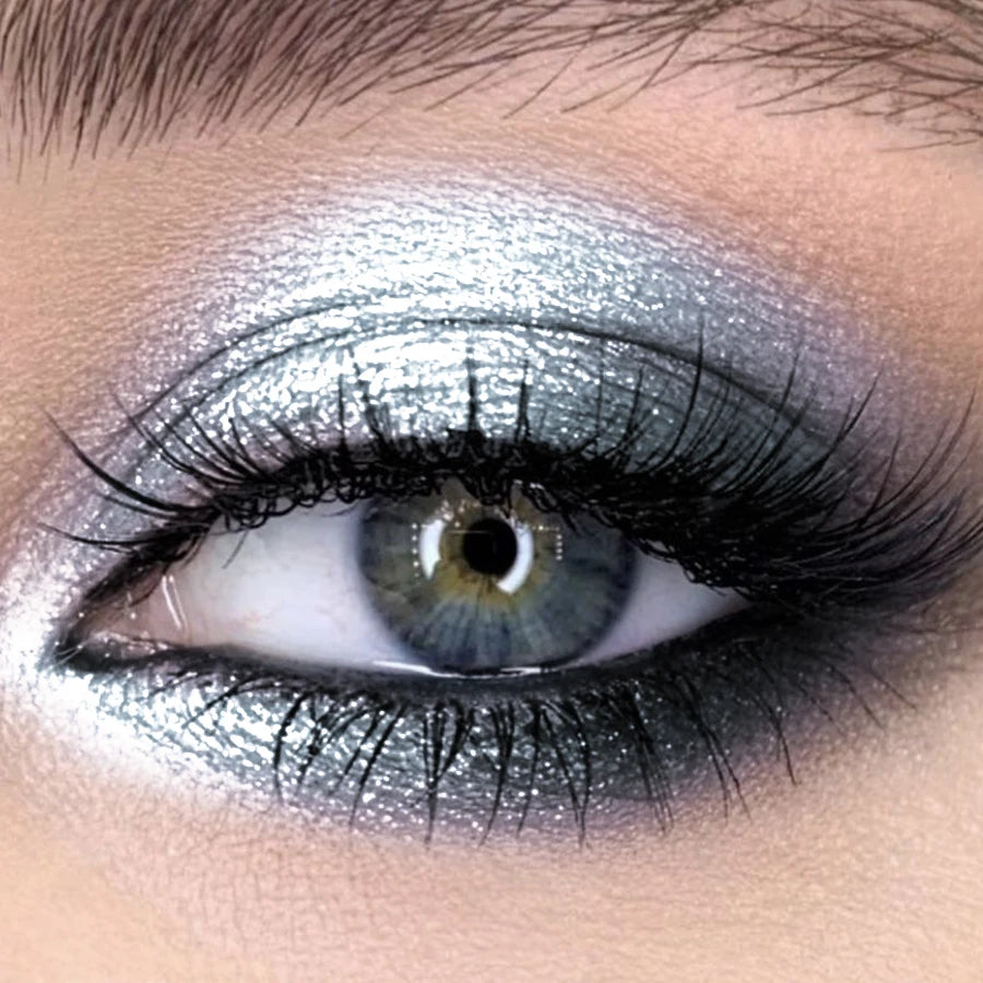 Primer plano de un ojo con sombra de ojos brillante plateada y azul glitter.