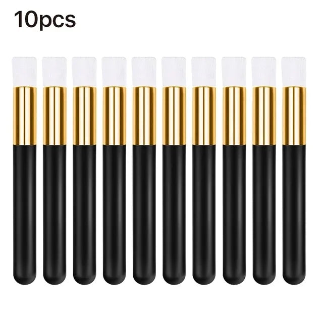 Ten black and gold eyelash extension cleaning brushes standing upright.