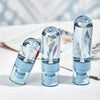 Three clear glass portable refillable fine mist spray bottles lined up on a white surface.
