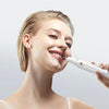 Eine Frau benutzt einen weißen Ultraschalldentalscaler zur Selbstreinigung ihrer Zähne.
