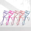 A row of five precision eyelash curlers in various pastel colors, including purple, pink, and blue, displayed on a white surf