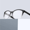 Une paire de lunettes de lecture noires multi-lentilles avec des verres clairs, sur fond gris.