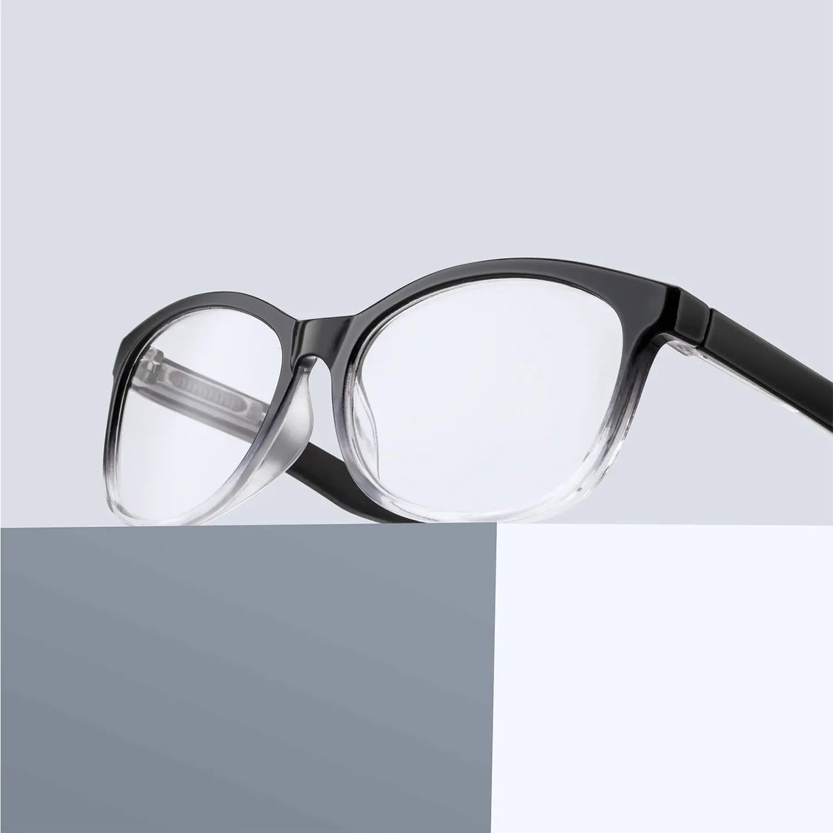Une paire de lunettes de lecture noires multi-lentilles avec des verres clairs, sur fond gris.