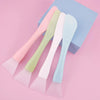 A set of five silicone facial mask brushes in pastel shades arranged on a light blue box.