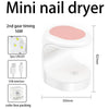 A white mini nail dryer with a pink heating element and various accessories shown in a box packaging.