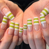 A set of white French style press-on nails with green stripes on a coffin shape shown on hands.