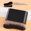 A close-up view of a black foundation makeup brush with dense bristles shown against a light background.