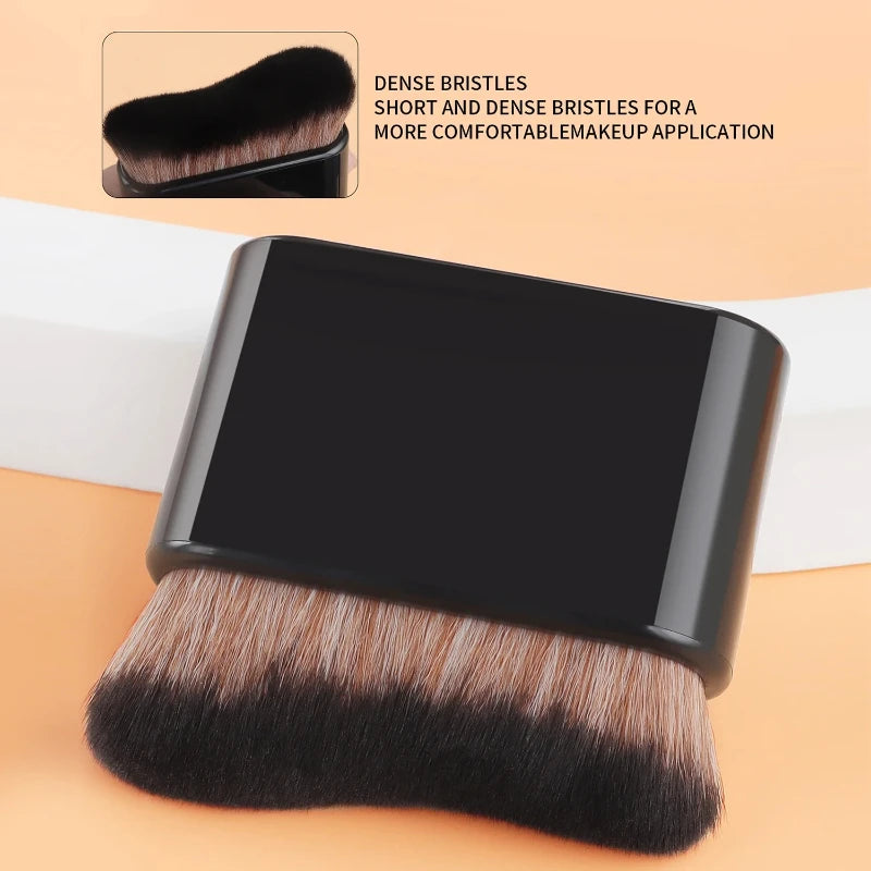 A close-up view of a black foundation makeup brush with dense bristles shown against a light background.