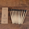 A box containing a set of ten natural bamboo toothbrushes is displayed on a wooden surface.