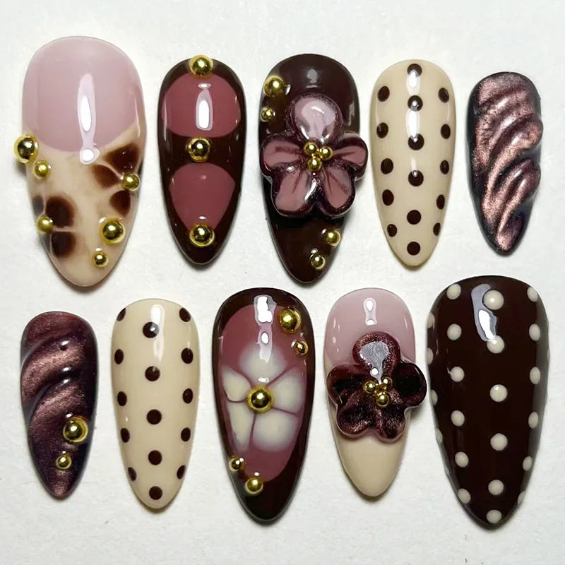Un set de 24 ongles press-on roses français à l'amande, avec divers motifs comme des pois et des accents floraux.