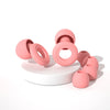 A collection of pink silicone earplugs in various sizes and shapes, displayed on a white surface.
