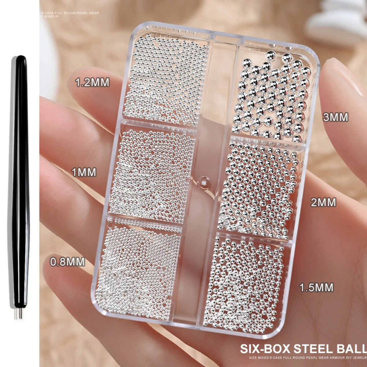 A clear box containing various sizes of round stainless steel beads for nail art decorations