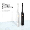 A pair of sleek, black and silver ultrasonic electric toothbrushes are displayed on a white marble surface.