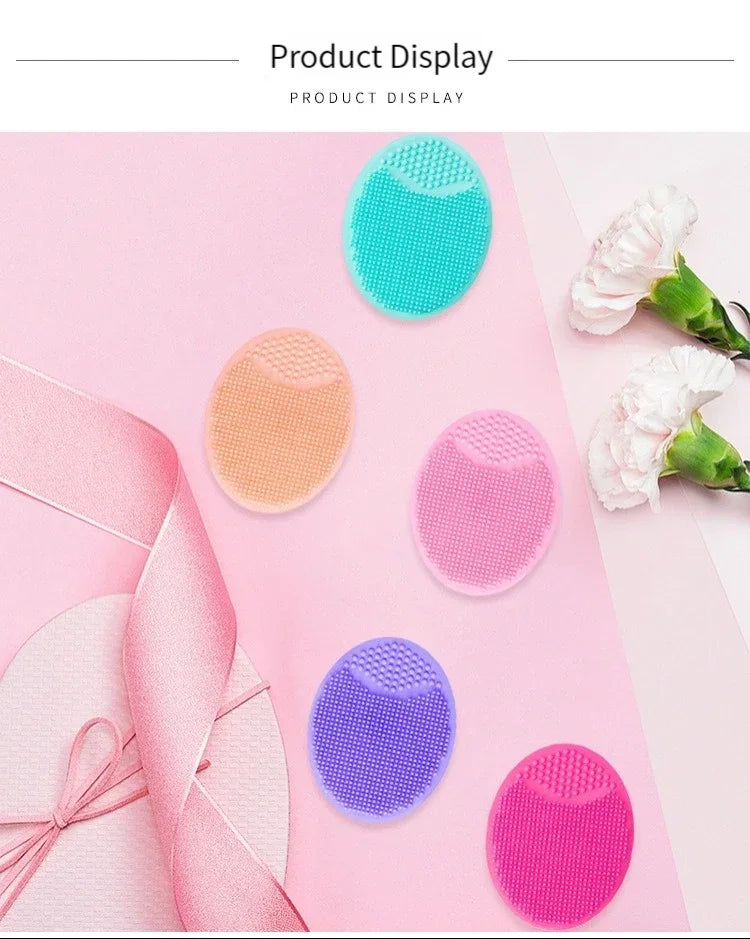 A display of various colored silicone facial cleansing brushes on a pink background.